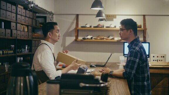 亚洲鞋店店员在柜台上与顾客交谈(慢镜头)