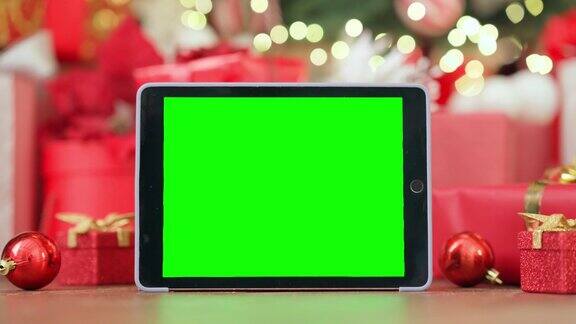 数字平板电脑模型绿色空白屏幕广告在圣诞桌的背景