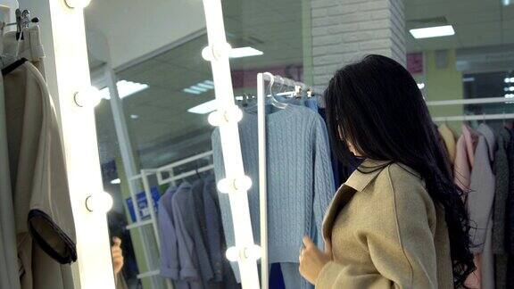 一名年轻女子在服装店的镜子前量大衣