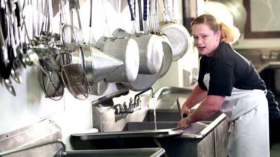 在商业厨房洗碗的妇女