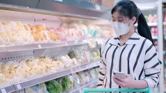 亚洲少女戴着口罩走在超市买杂货