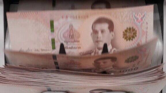 近镜头的泰国钞票一千泰铢(100泰铢)计数在钞票柜台机器货币计数银行柜台机械纸币金融市场