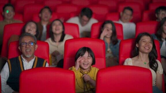一位活跃的亚洲华人老人和他的孙女笑着在电影院看电影