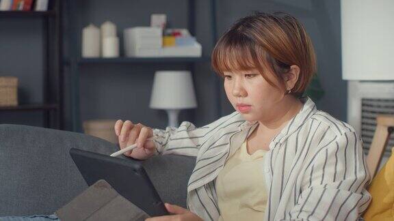 自由亚洲女士休闲装使用平板电脑在线学习在客厅在家里