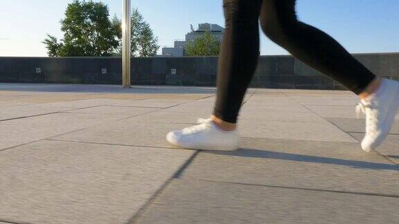 穿着白鞋的女人的腿走在干净、空旷的人行道上