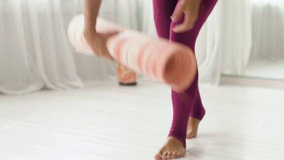 在瑜伽室或健身房卷起垫子的女人