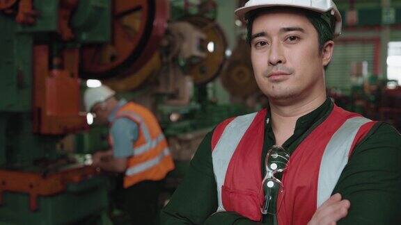 一位白人男性专家工程师的肖像戴着安全帽和背心在工业工厂辛勤工作