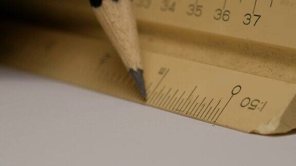 特写使用三角形比例尺与铅笔在白纸上画出建筑图纸、模型规模1:50