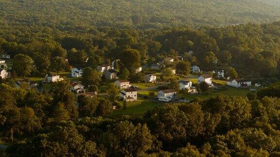 在宾夕法尼亚州波科诺斯的阿巴拉契亚山脉的一个小乡镇的远景在傍晚许多家庭的屋顶都安装了太阳能电池板摄像机移动的航拍镜头