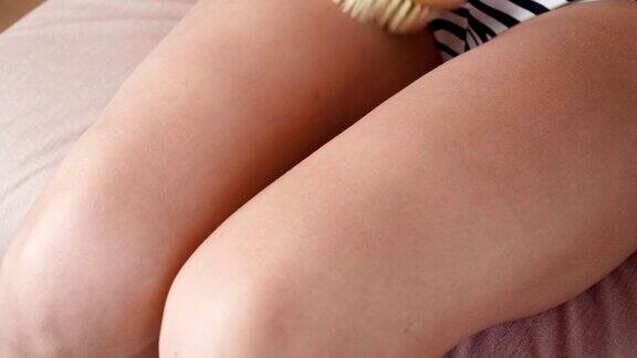 年轻苗条的女人用木刷在她的腿上做瘦身按摩护肤、美容理念关闭了