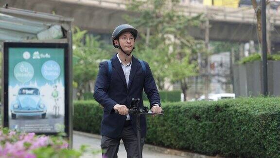 亚洲男子在大城市骑电动踏板车