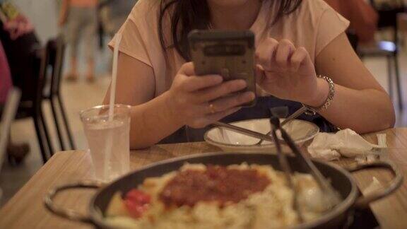 亚洲女性用智能手机给食物拍照
