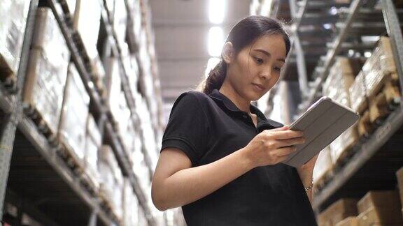 亚洲女工人在仓库用平板电脑检查物资
