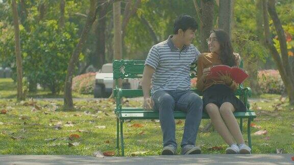 快乐的小情侣在公园的长椅上放松爱