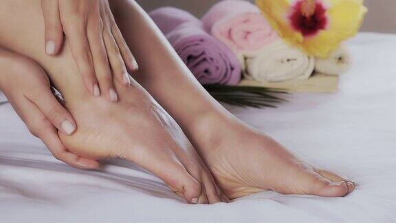特写的西班牙裔年轻女子涂抹保湿霜在她的脚后洗澡