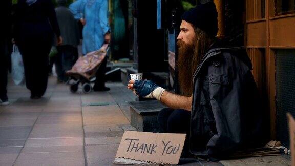 无家可归的人拿着“谢谢”纸板在拥挤的街道上乞讨