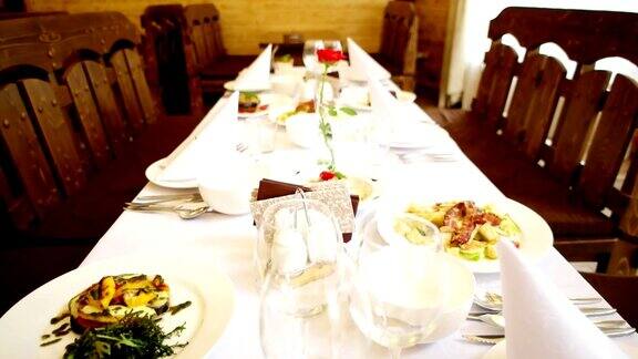 庆祝餐桌上餐盘摆在桌上刀叉、刀叉、刀叉摆在盘子旁边肉、鱼、沙拉摆在洁白美丽的餐桌上