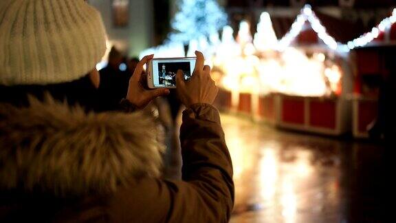 美丽的女孩拿着手机在冬天的街道上与圣诞灯-慢镜头