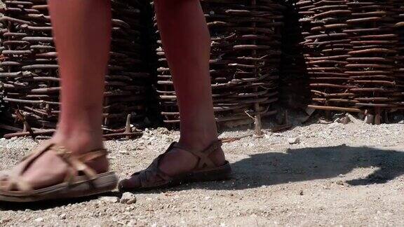 一个穿着凉鞋的女人疲倦地走在战壕旁边的地上