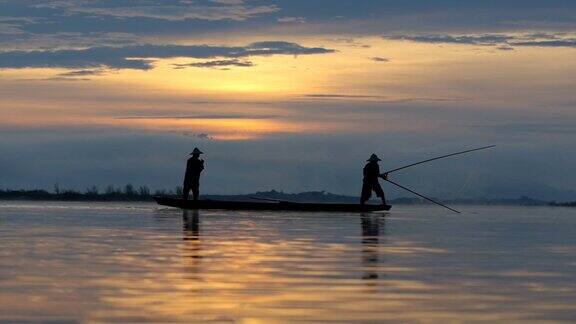 高清影像剪影两个身份不明的传统渔民准备在船上捕鱼