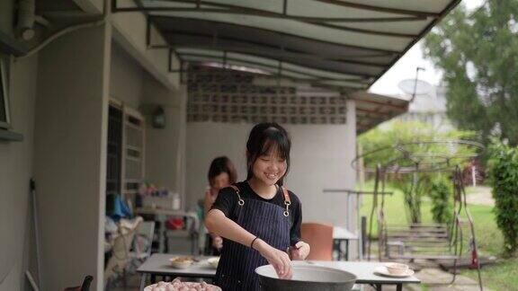 亚裔华人母亲和女儿在后院厨房准备食物女儿在向母亲学习