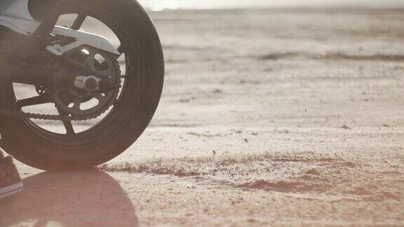 摩托车手在沙漠中轮胎烧坏慢镜头专业摩托车手在地面上滑行摩托车手在摩托车上表演特技