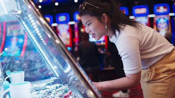 近距离亚洲女性休闲享受周末玩投币老虎机在娱乐街机游戏赌场钱币游戏