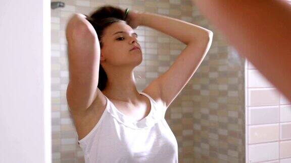 一名年轻女子在镜子前梳着健康的头发打呵欠