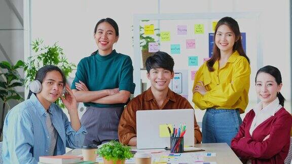 描绘快乐亚洲商业创意企业家团队会议和头脑风暴在办公室亚洲青年团队合作伙伴的微笑和看着相机