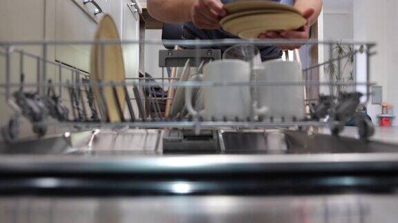 洗碗机里干净的盘子的特写镜头一个男人在端盘子