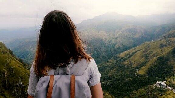 镜头围绕着年轻平静的女游客背包享受风吹过的头发在史诗般的斯里兰卡山景
