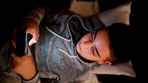 青少年躺在沙发上用手机和朋友聊天社交网络