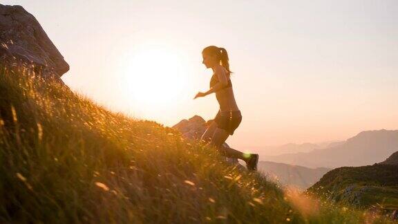 年轻的女运动员在日落时跑上山