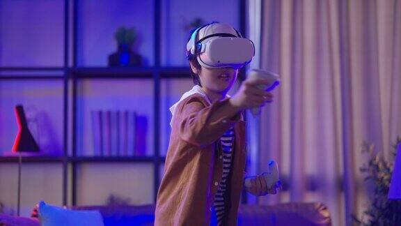 亚洲儿童男孩戴着VR或虚拟现实眼镜头戴耳机站在家里客厅的电视机前玩电子游戏在隔离期的技术和创新概念霓虹灯夜的生活方式
