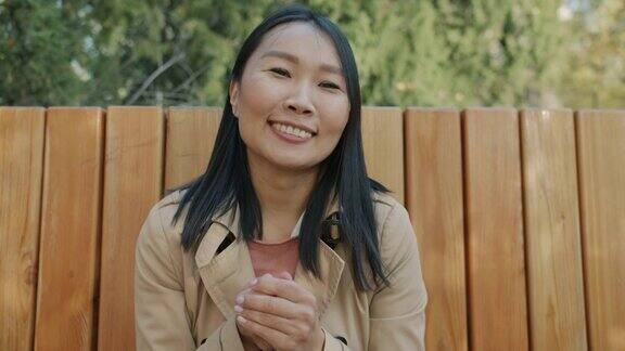 快乐的亚洲女商人肖像在城市公园外面在线视频电话