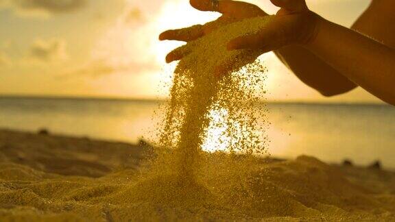 慢镜头:一个女人在度假时让粗糙的沙子从手指间滑过