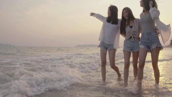 微笑快乐的亚洲朋友群年轻的女人一起走在海边的海滩上夏天度假日落剪影黄昏假日旅游享受生活周末活动人们的生活方式慢镜头4K