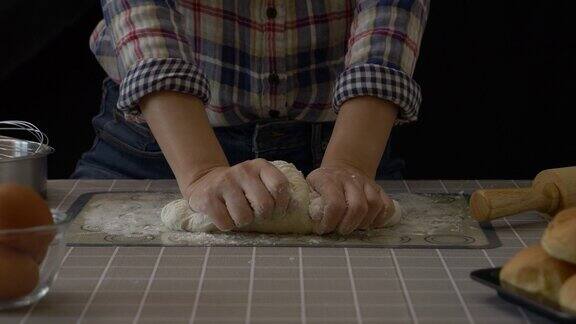 用面团制作的手工面包面粉撒在面团上在厨房用烘焙设备工具手工揉制面包黑色背景专业面包师在工作中的面包制作过程60fps