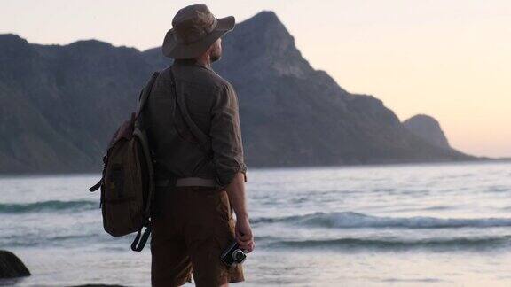 一个旅行家背着背包站在大海上欣赏着夕阳的狂野爱情