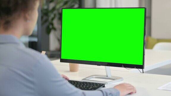 后视图非洲妇女使用桌面与绿色色度键屏幕