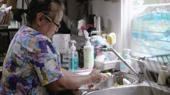 慢镜头:祖母在家里的厨房水槽里洗盘子