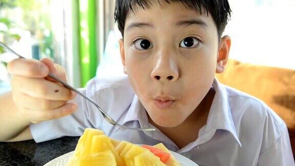 亚洲可爱的小男孩正在吃一片成熟的菠萝