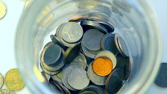 特写俯视图慢动作扔硬币泰国钱在罐子概念储蓄