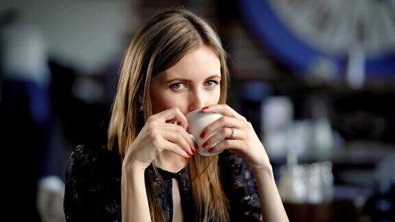 拿着咖啡杯的可爱女孩年轻漂亮的女人坐在咖啡馆里喝着咖啡