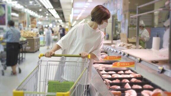 一个女人戴着一次性医用口罩在超市购物