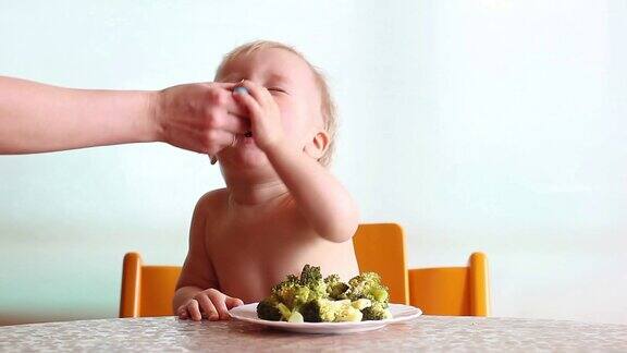 妈妈用叉子喂花椰菜宝宝吃得愉快有趣快乐的孩子白色的背景