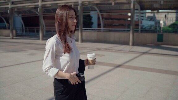 自信的年轻女商人一边喝咖啡一边在城市里散步