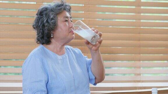 亚洲老年妇女在家厨房喝牛奶退休生活方式积极的老年人健康