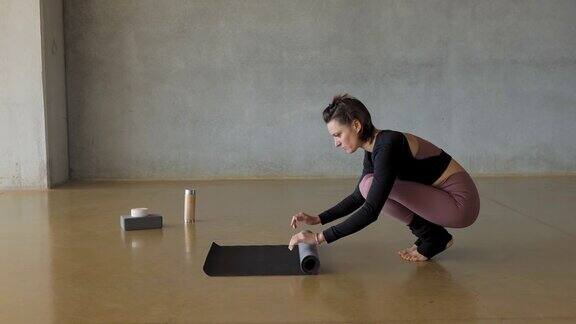 在健身中心上完瑜伽课后一个女人正在折叠垫子