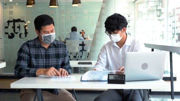 亚洲同事在新冠肺炎疫情期间戴着口罩上班